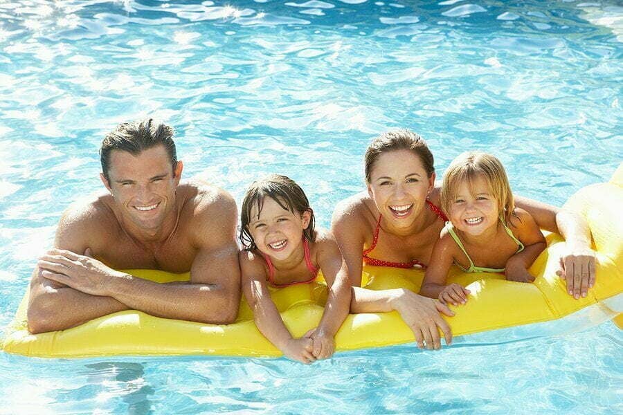 Parents withchildren inthe pool McCormack Realty Renters Choice Homes A young family having fun in their rental homes backyard swimming pool